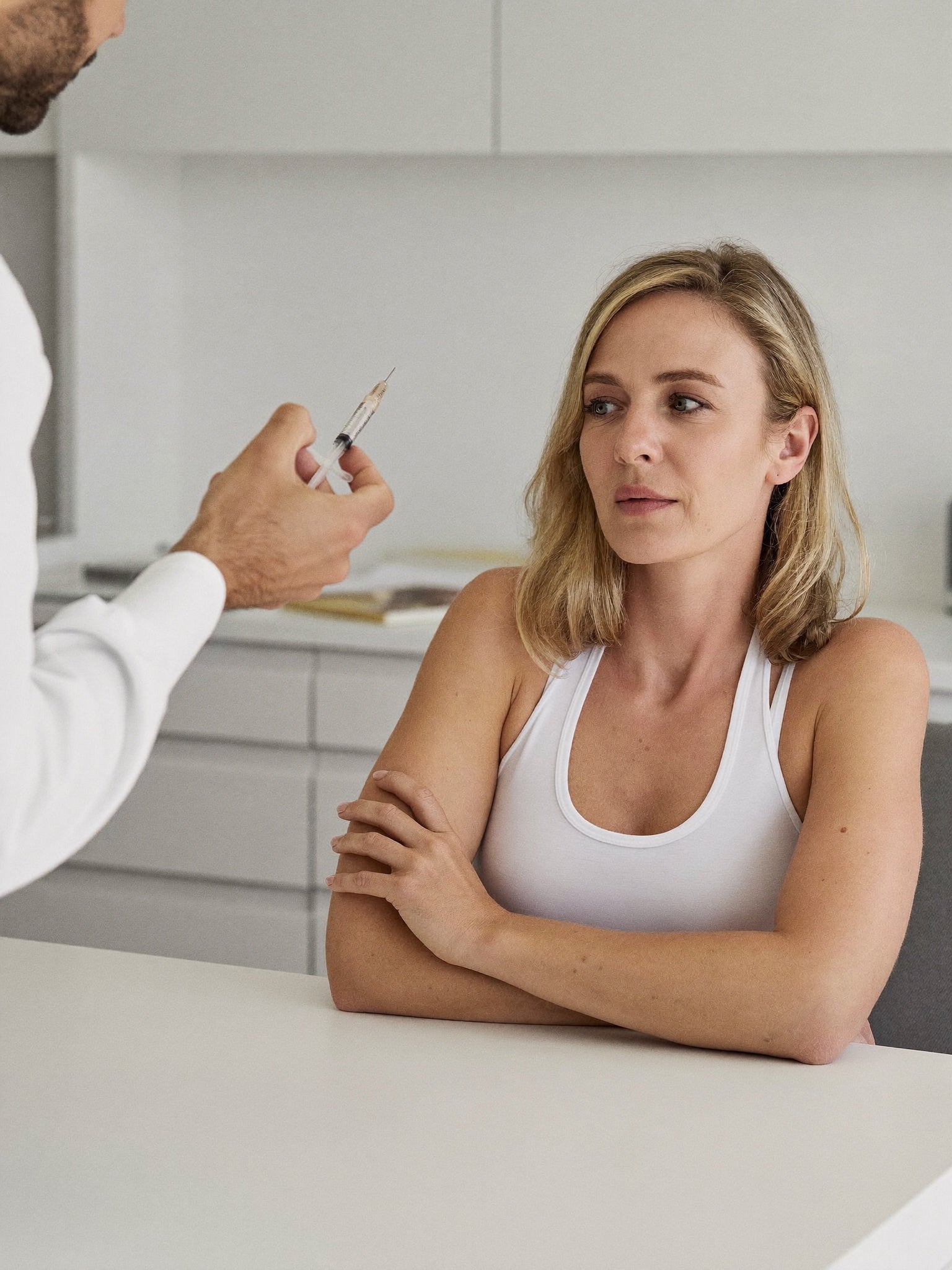 A woman at a clinic consultation declining a filler syringe