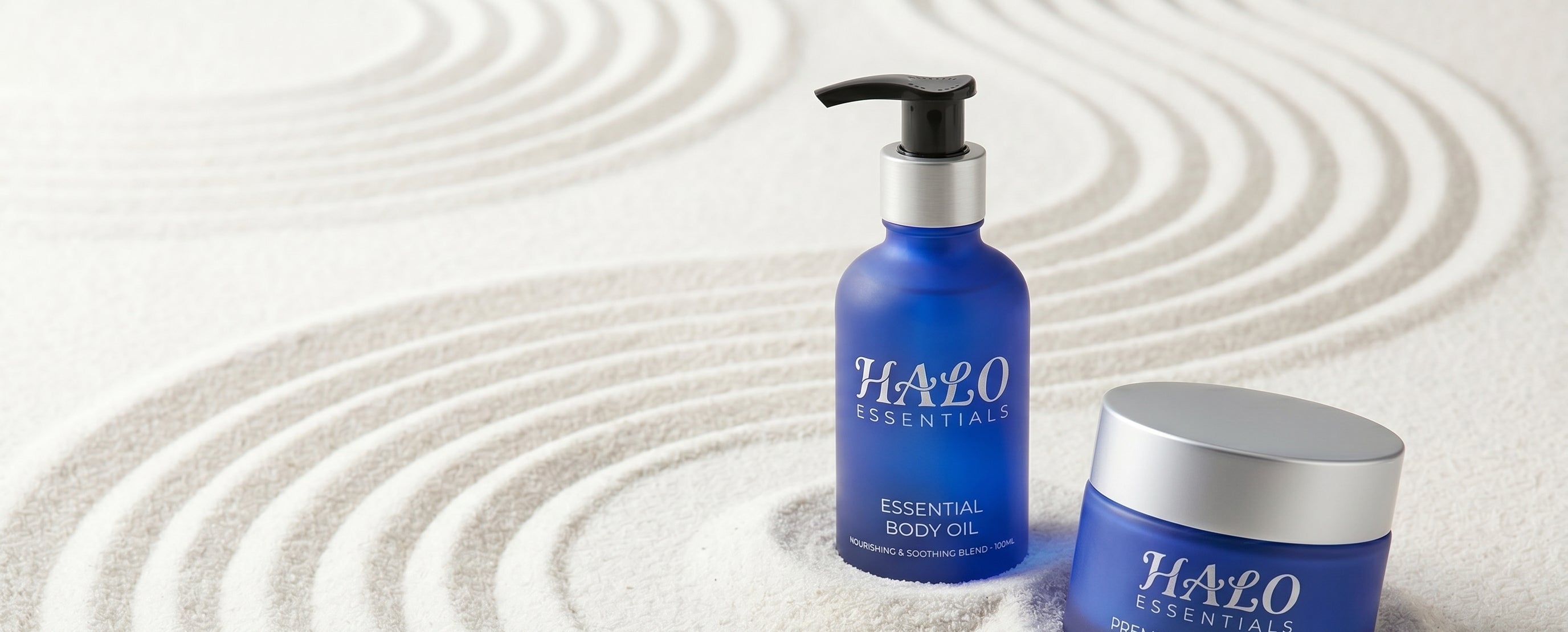 Halo Essentials body oil and face cream on raked sand